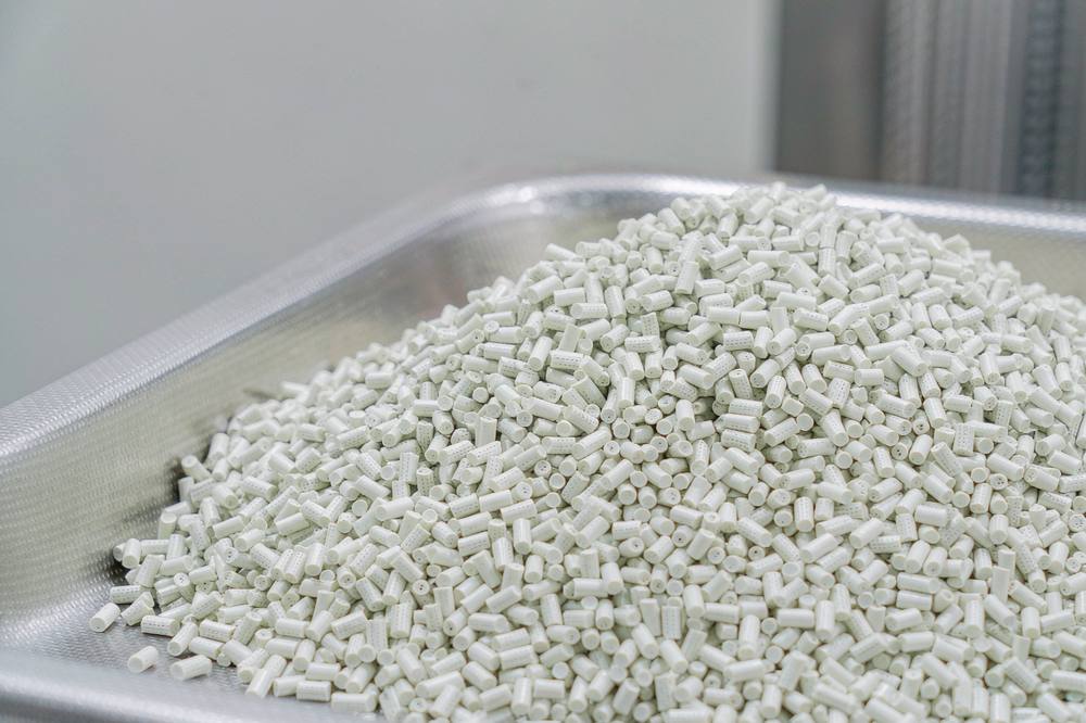 pale glass fibre reinforced thermoplastic pellets in a stainless steel tray in a compounding laboratory