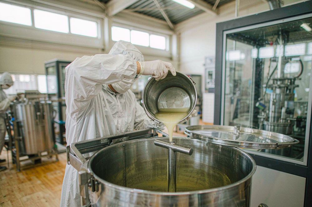 Operator blending a phenolic modifier into an amine hardener in a stainless steel mixing vessel